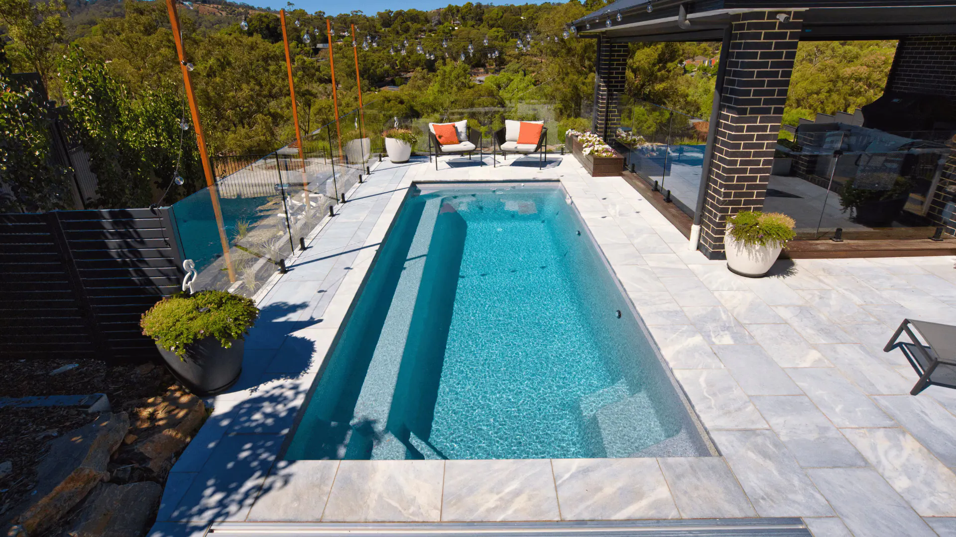 Outdoor pool with umbrella, lounge seating, and sunny yard