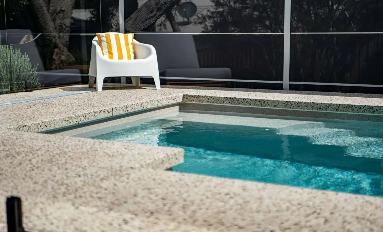 Small spa pool with textured deck and white chair setup